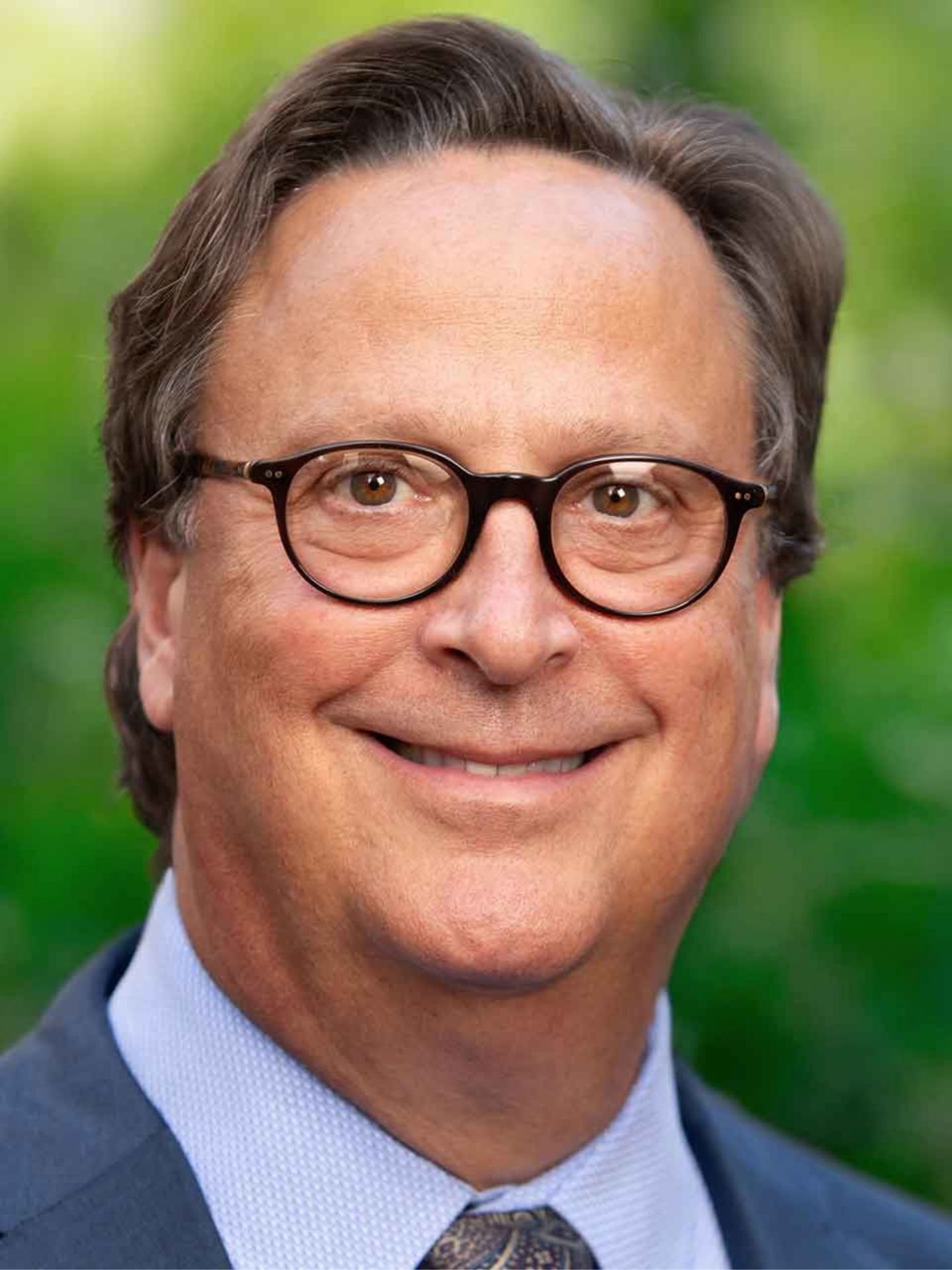 A man with glasses smiling