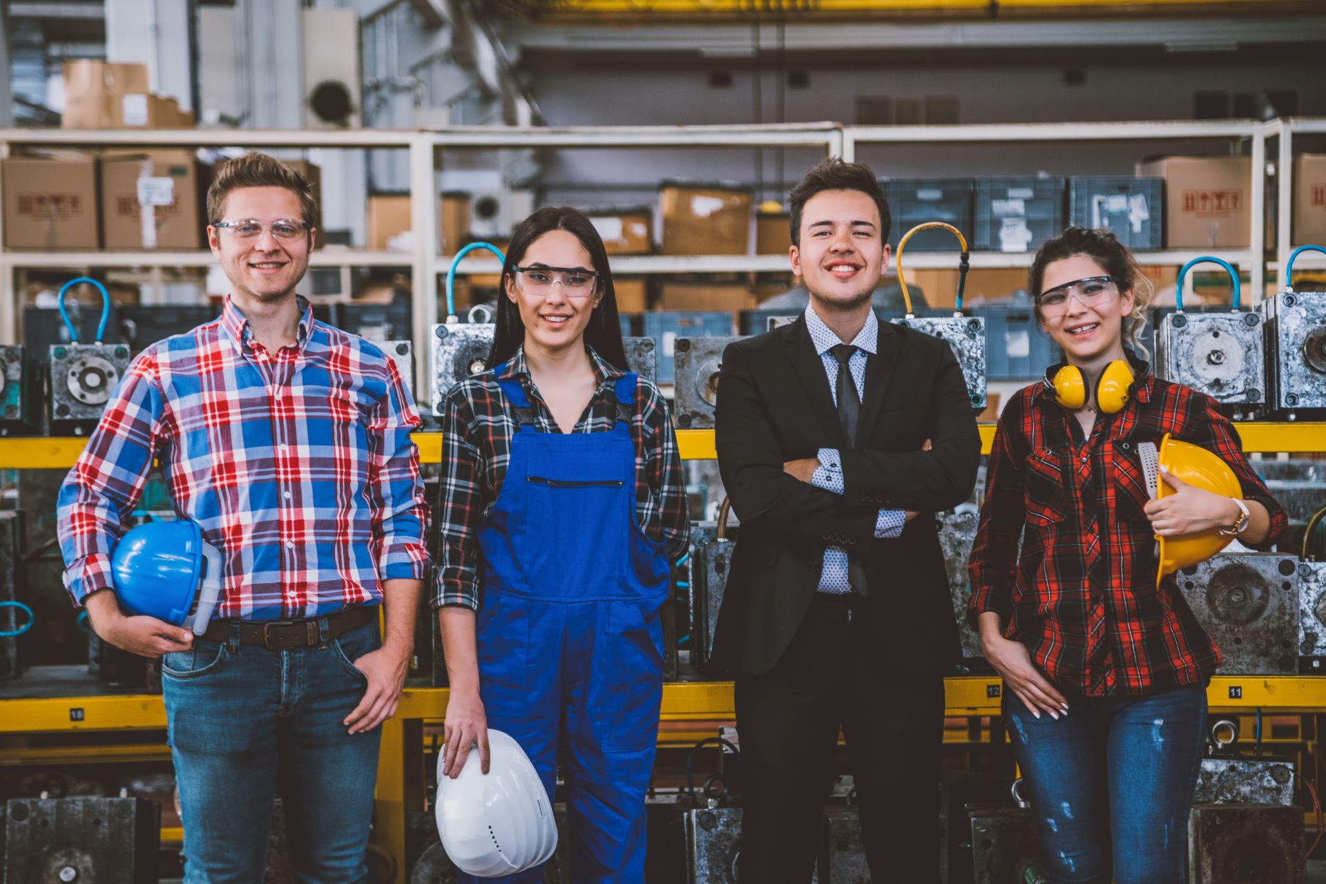 Four people smiling at the camera in a factory