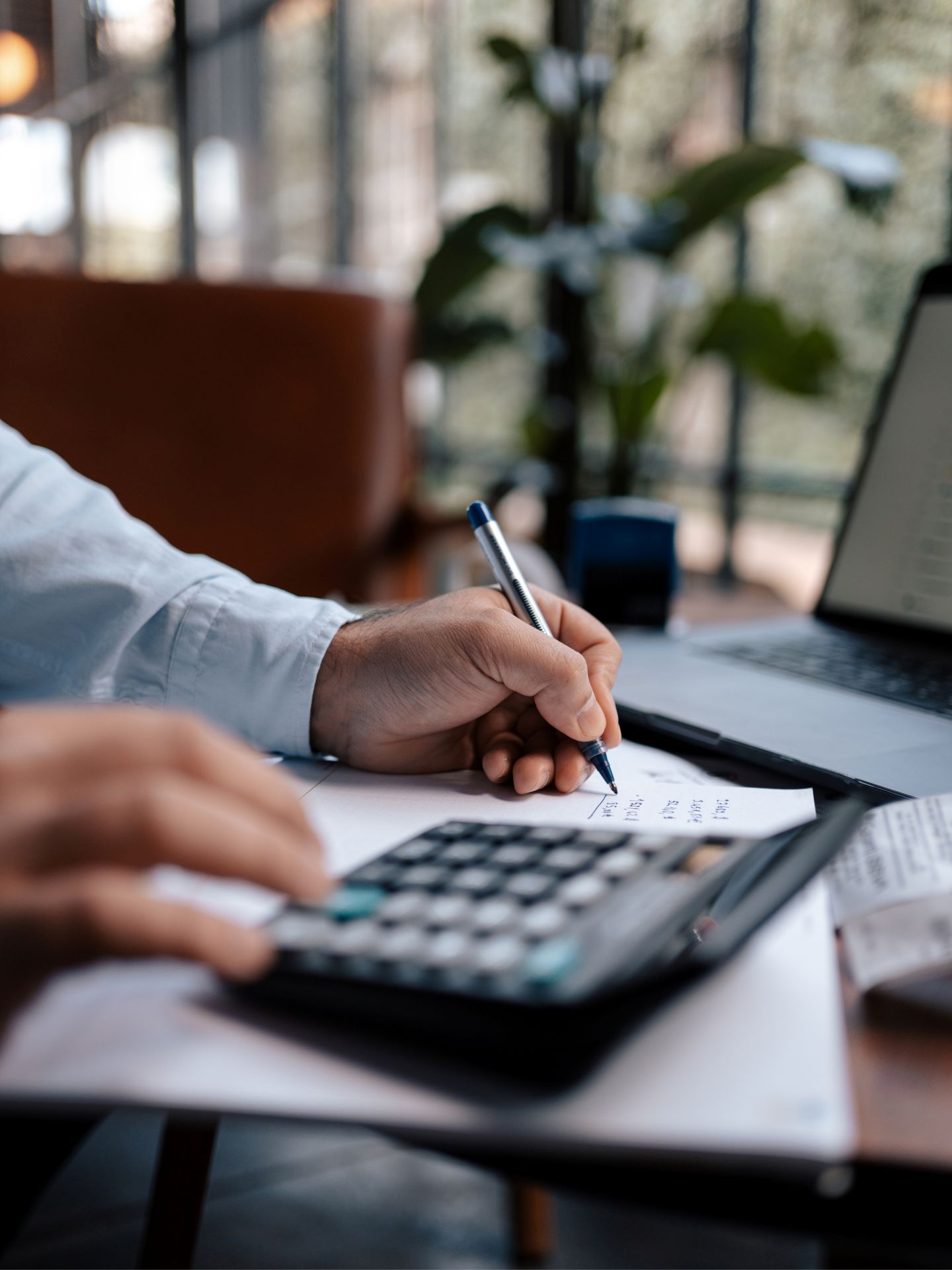 A man writing at his desk with a calculator next to him