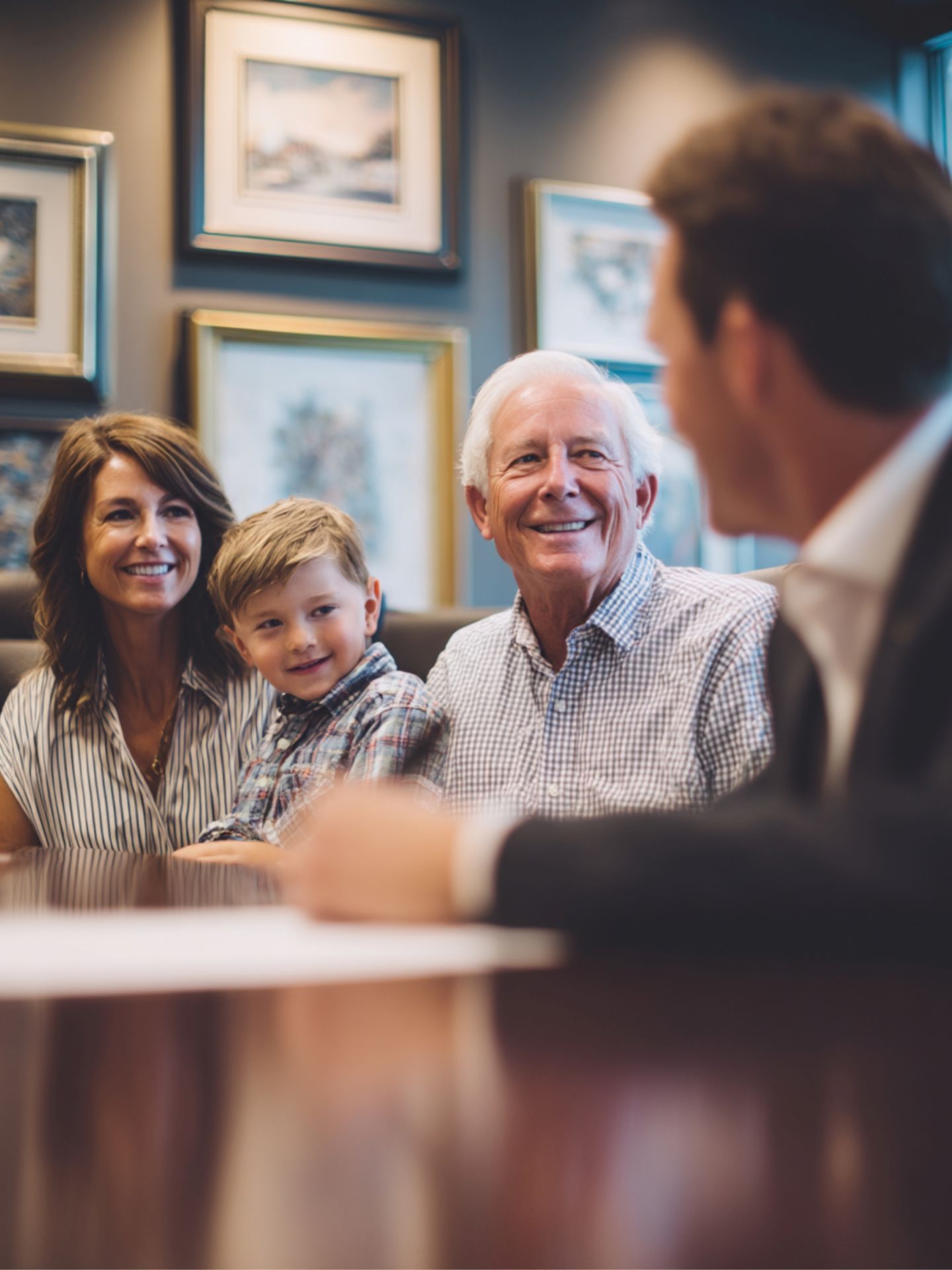 An elderly man, a middle-aged woman, and a young child meeting with a business man in a suit