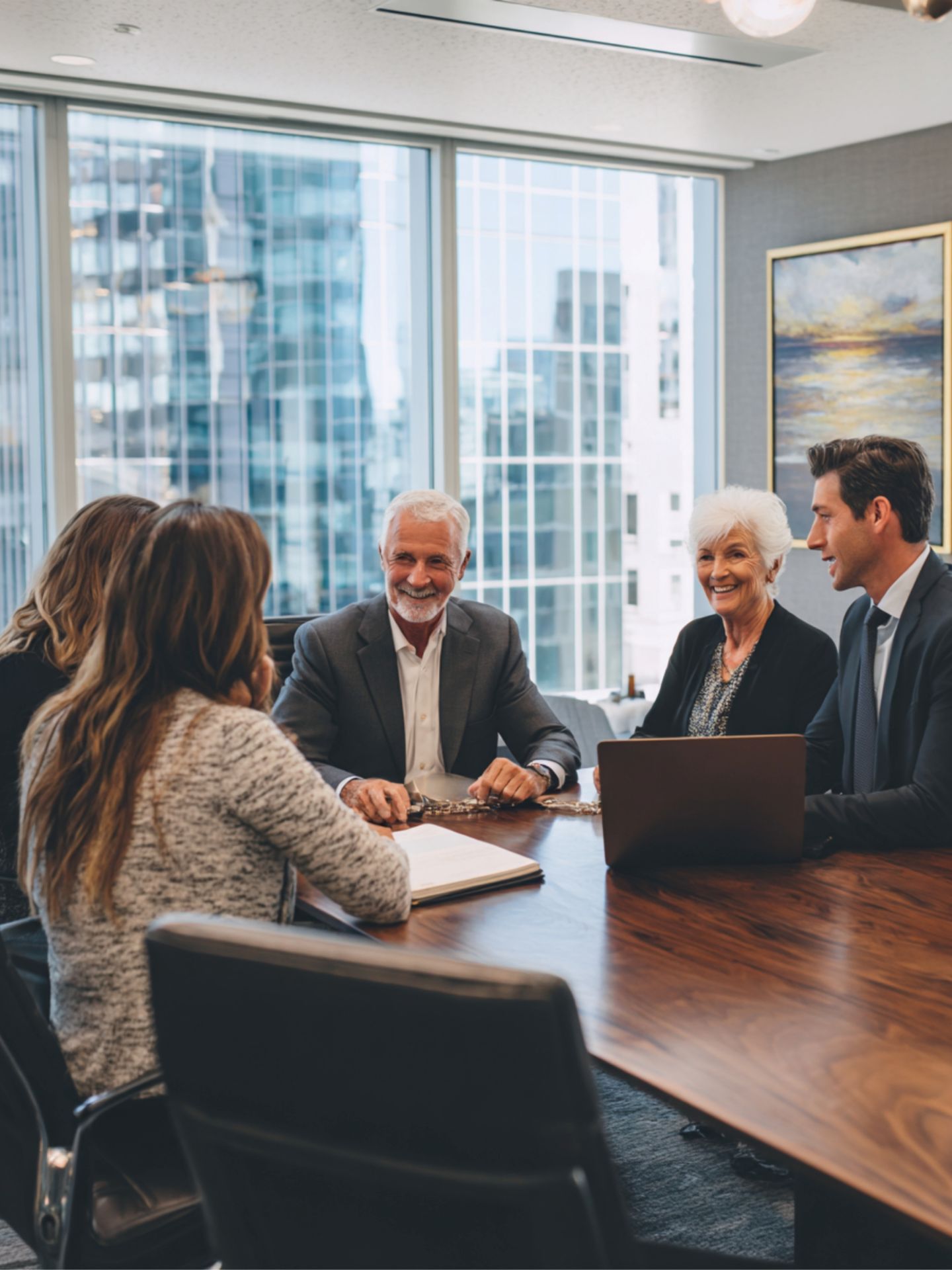 An elderly couple sitting in a meeting room with a group of business people.